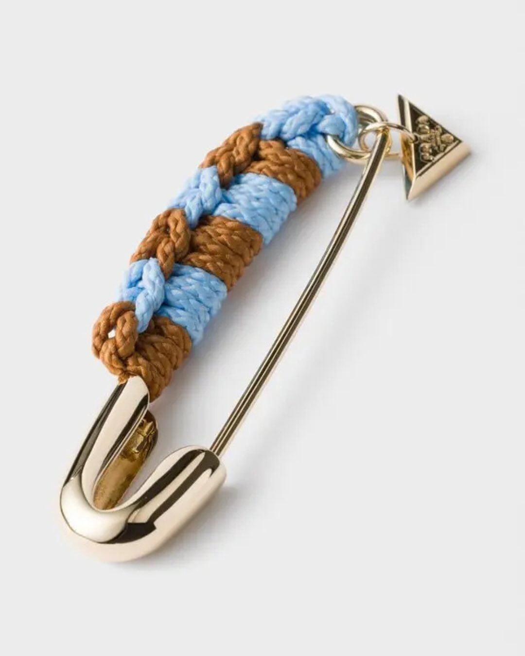 प्राडाने लाँच केलेली ही पिन सोनेरी रंगाची आहे. तिला थोडं आकर्षक बनवण्यासाठी त्यावर रंगीत लोकरासारख्या धाग्यांनी डिझाईन त्यावर डिझाईन केले आहे. त्यावर एक छोटासा प्राडाचा (Prada) चार्मही लावण्यात आला आहे.