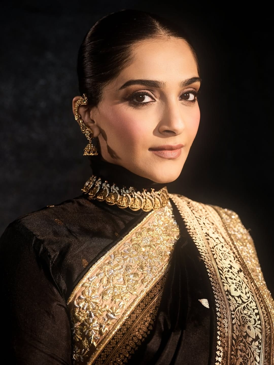 अबू जानी संदीप खोसला आणि स्वदेश इंडिया यांनी डिझाइन केलेल्या काळ्या ब्रोकेड बनारसी साडीत सोनम खूपच सुंदर दिसत आहे. बेज, सोनेरी आणि चांदीच्या जरदोजी बॉर्डरने साडीला एक शाही स्पर्श दिला आहे.