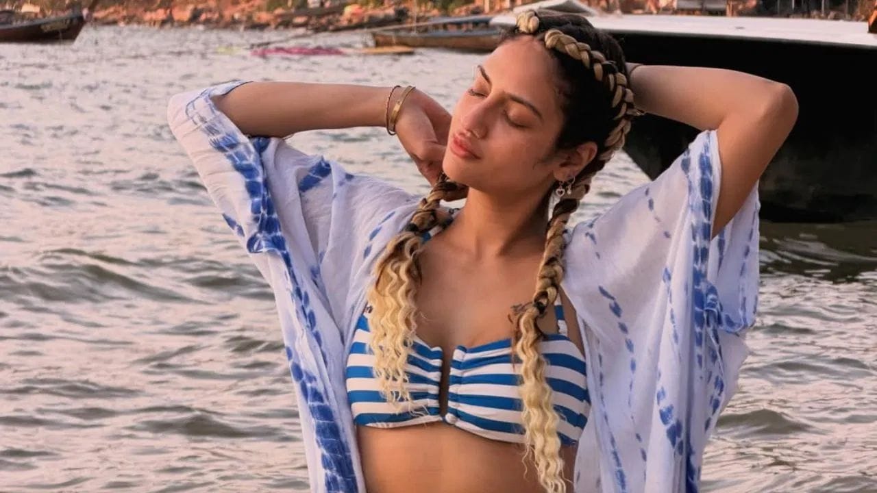 नुसरत जहाँ हीने या फोटोत थ्री पीस बिच ड्रेस परिधान केला आहे.यात नुसरत जहाँ हीने व्हाईट आणि ब्ल्यु कलरचा एक किमोनो कव्हर-अप, व्हाईट आणि ब्ल्यु कलरचा एक स्ट्रीप्ड बिकनी टॉप आणि व्हाईट कलरचा डेनिम शॉट्रस घातलेला दिसत आहे. 