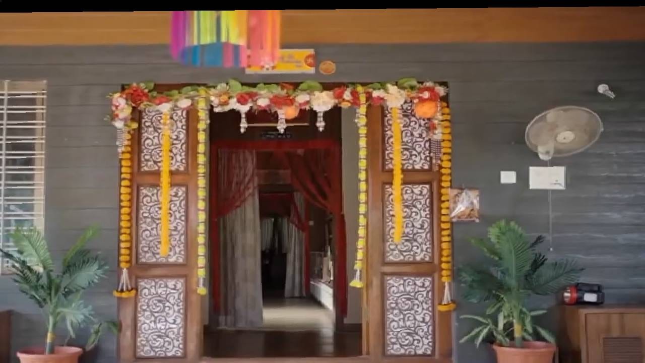 त्यांच्या घराच्या प्रवेशासाठी सुंदर लाकडी दरवाजा असून त्यावर खूप छान, नाजूक डिझाईन, कलाकुसर आहे. प्रवेशद्वारावर असलेलं  फुलांचं छानसं तोरणही येणाऱ्याचं लक्ष वेधून घेतं. 