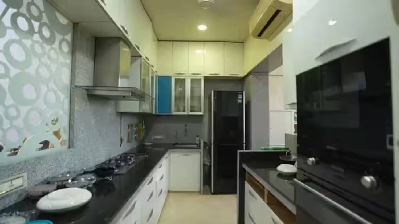 घरातील किचनही साधं, स्वच्छ आणि आधुनिक आहे. पांढऱ्या कॅबिनेट्ससोबत काळ्या-ग्रे काउंटरटॉपचा वापर करण्यात आला आहे. मॉड्युलर सेटअपमध्ये ओव्हन, चिमनी आणि फ्रिज व्यवस्थित बसवण्यात आले आहेत.