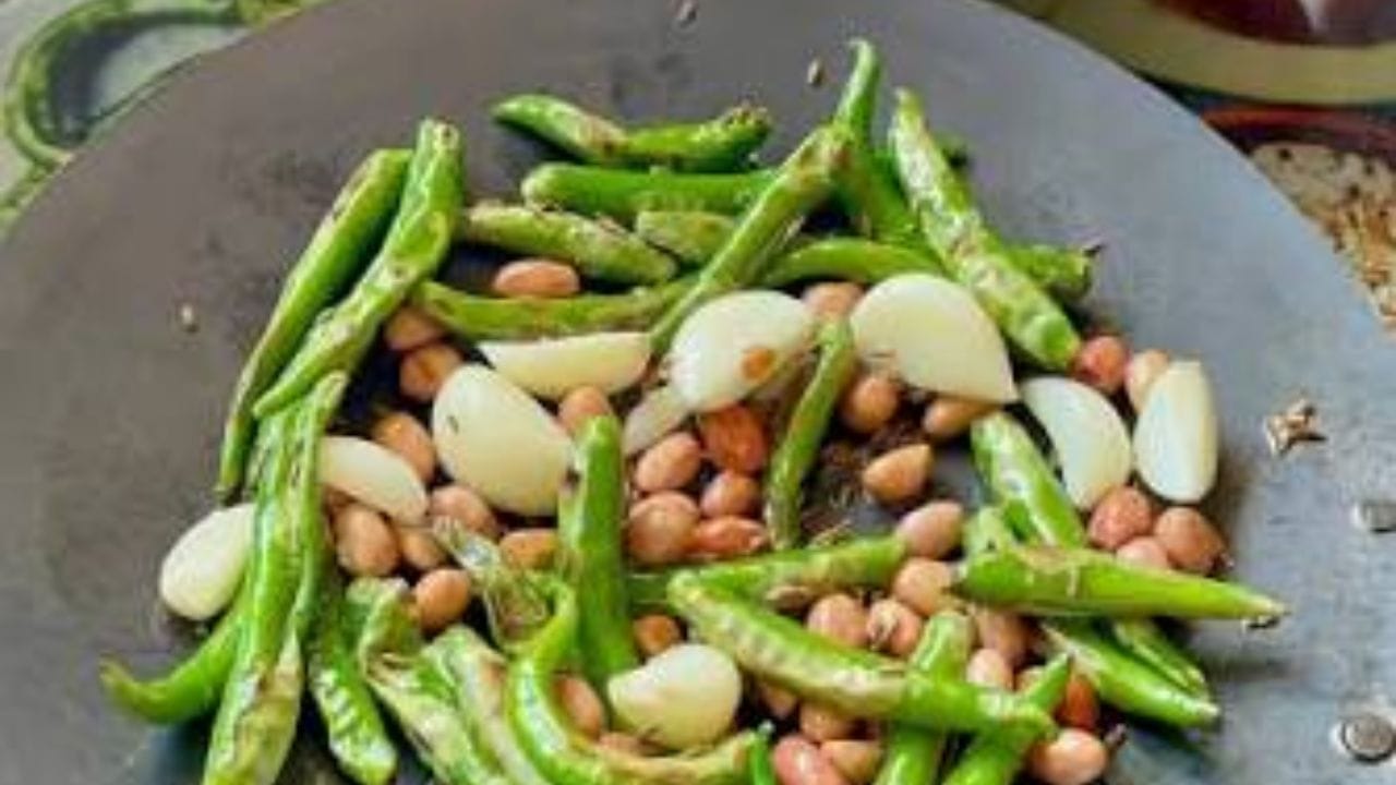 सगळ्यात आधी हिरव्या मिरच्या स्वच्छ धुवून छान सुकवून घ्या.  तवा गरम करून त्यावर थोडंसं तेल सोडा आणि त्यात हिरव्या मिरच्या आणि लसूण घाला. मंद आचेवर मिरच्या थोड्या भाजून घ्या. मिरच्यांना सालावर हलके काळसर डाग पडले आणि लसूण छान भाजली कि काढून घ्या. 