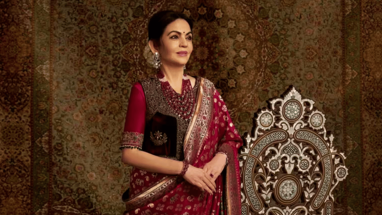 नीता अंबानी यांनी मॅजेंटा आणि सोनेरी रंगाची आशावली सिल्क साडी नेसली. ही साडी गुजरातच्या पारंपरिक विणकाम कलेचे उदाहरण आहे. मनीष मल्होत्रा यांनी स्वदेशसोबत मिळून ही साडी तयार केली.